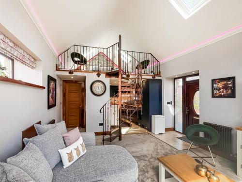 a living room with a couch and a spiral staircase at West Mains Barn - Uk51957 in Kilbirnie