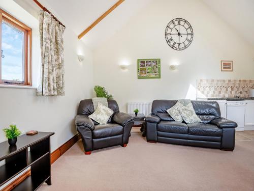 a living room with two leather chairs and a tv at Hayloft - Uk49909 in Blandford Forum