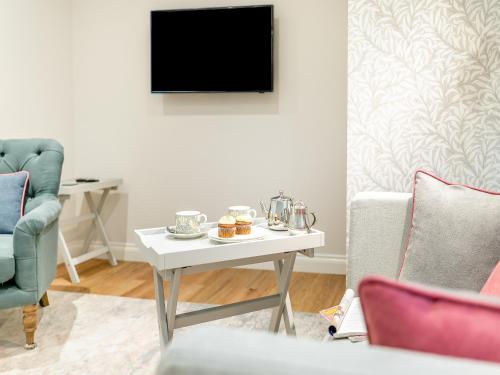 a living room with a table and a tv at Anne's Cottage in Strines