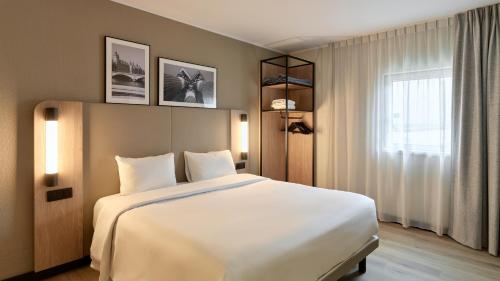 a bedroom with a large white bed and a window at Campanile PRIME - Paris - Porte de Bagnolet in Bagnolet