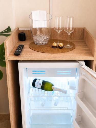 an open refrigerator with a bottle of wine and two glasses at Domus REA Bracciano - Self Check-in H24 in Bracciano