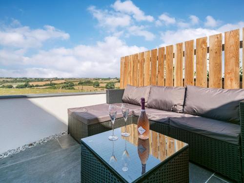 a patio with a couch and wine glasses on a table at The Old Coach Garage in Gerrans