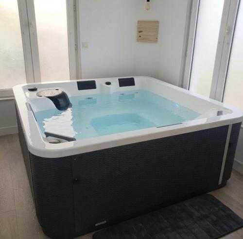 a jacuzzi tub with a black and white bathtub at La Casa des Frangins in Saint-Romain-de-Colbosc