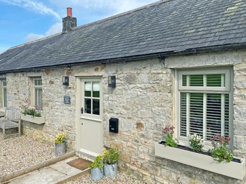 a stone cottage with a white door and windows at Night Sky Cottage in Kielder