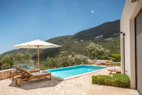 a swimming pool with an umbrella and chairs next to a house at Villa Dara and Todd in Sivota