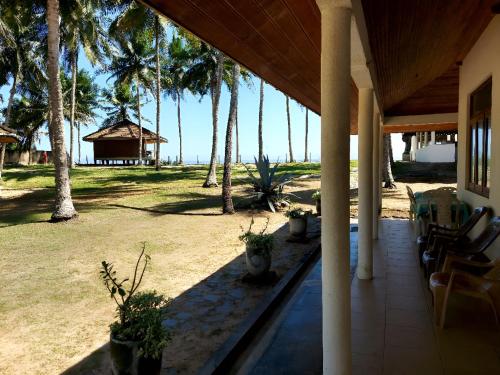 a porch of a house with palm trees and a gazebo at Coconut Grove Beach Cabanas in Hungama