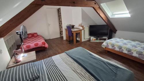 a attic room with two beds and a television at Les Pâquerettes in Dinan