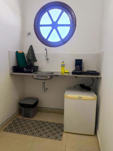 a bathroom with a sink and a window on the wall at Casinha Guest House in Saquarema