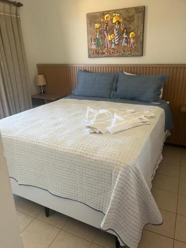 a bedroom with a large bed with a white comforter at Praia do Forte - ap Bali Bahia 107 in Praia do Forte