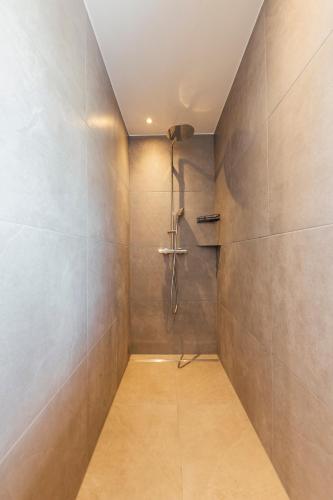 a bathroom with a shower and a tile wall at Bodensee Bergblick Nest by Stadtlandnest in Lochau