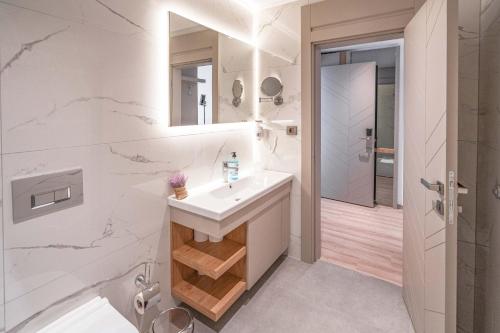 a white bathroom with a sink and a shower at Riversea Suite & Hotel in Lara