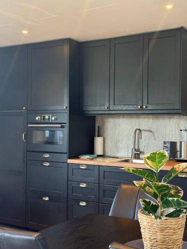 a kitchen with blue cabinets and a table with a plant at Camp Saltstraumen-Elvegård in Bodø