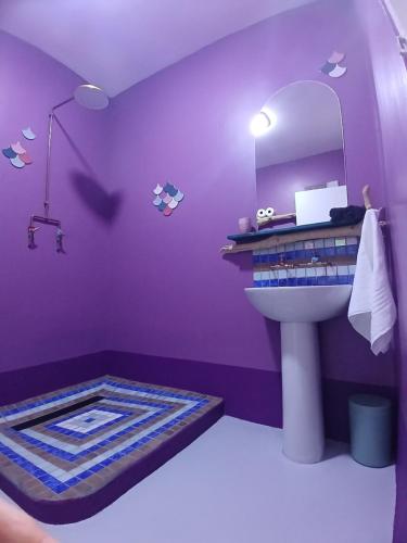 a purple bathroom with a sink and a mirror at The Laughing Mermaid in Coffee Bay
