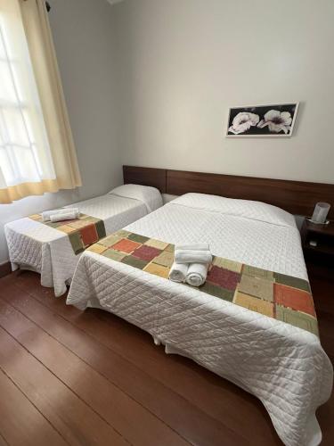 two beds in a bedroom with a quilt on them at Pousada Luar da Serra in Valença