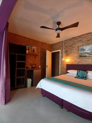 a bedroom with a bed and a ceiling fan at The Laughing Mermaid in Coffee Bay