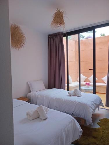 two beds in a room with a window at APPARTEMENT surf camp pour les familles in Oualidia