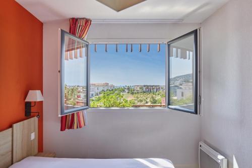a bedroom with a bed and a large window at Résidence Odalys Terra Gaia in Sète