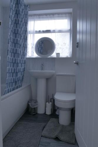 a bathroom with a sink and a toilet and a window at Modern 3BDR Home l Sleeps 5 l Free Parking l Close to Train station and Shops in Worksop