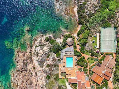 an aerial view of a house on a cliff next to the ocean at CASA MUGHETTO R5055 WiFi, seafront, private sea access, swimming pool in La Maddalena