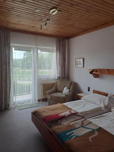 a bedroom with a bed and a chair and a window at Haus Bärnthaler in Faak am See