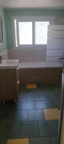 a bathroom with a tub and a sink and a window at Le Mazet in Nohèdes