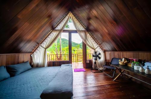 a bedroom with a bed in a room with a window at Leaf Village & Farm Làng Lá in Danang