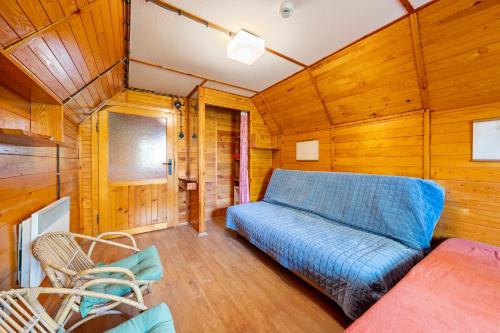 a living room with a blue couch and wooden walls at Chatka Kačka in Jedovnice