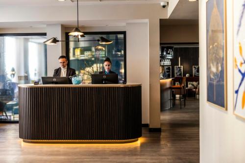 two men sitting at a reception desk with laptops at Motel One Copenhagen in Copenhagen