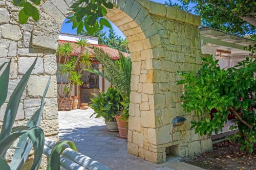 an archway in a stone wall with potted plants at Masseria L'Uliveto Agri Resort in Otranto