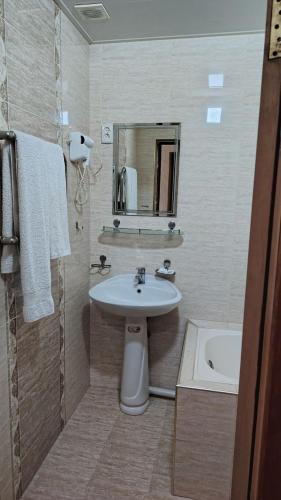 a bathroom with a sink and a mirror and a tub at Comfort Continent in Oktyabrʼ