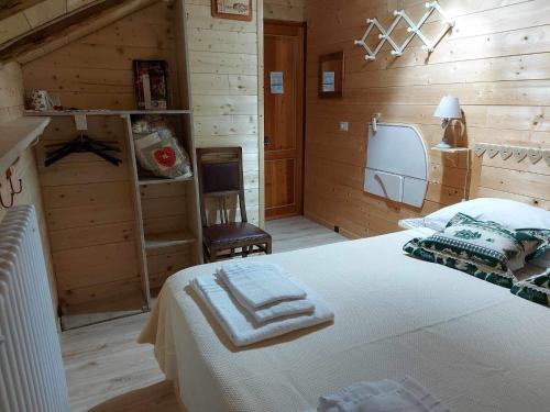 a bedroom with a white bed and a chair at B&B ABETE BIANCO in Auronzo di Cadore