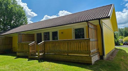 a small yellow house with a large deck at Gårdsjö 5 in Gårdsjö