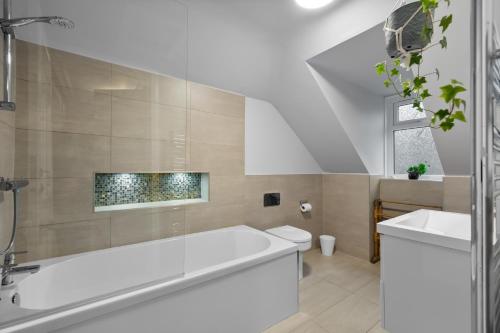 a bathroom with a white tub and a sink at Hermitage Suite - Stylish Shared Accommodation in Dundee
