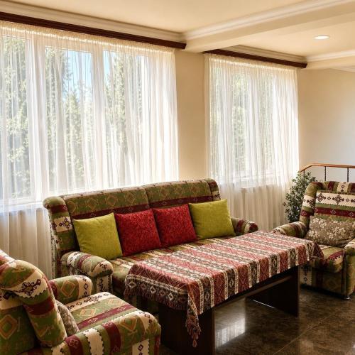 a living room with a couch and chairs and windows at Zanger Hotel in Goris