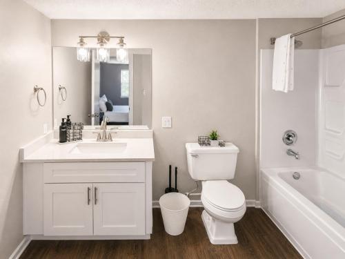 a white bathroom with a toilet and a sink at Maple n Main Hoover Modern 2BR Escape 2E in Hoover