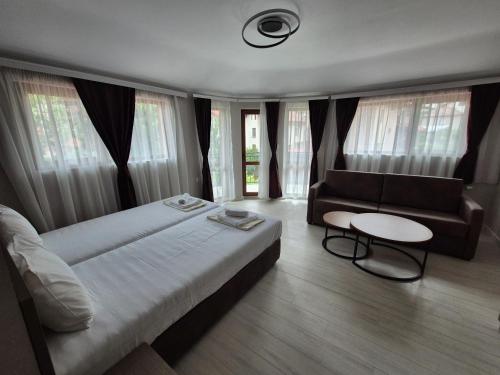 a bedroom with a bed and a couch and a table at Yuliya Guest House in Sapareva Banya