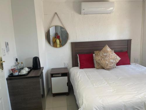 a bedroom with a bed with a mirror and a table at Cradle Mount Hotel Suites in Muldersdrift