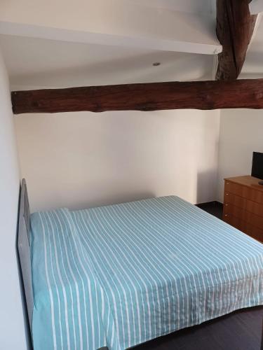 a bedroom with a bed with a blue striped sheet at Scoglietti Loft in Ventimiglia
