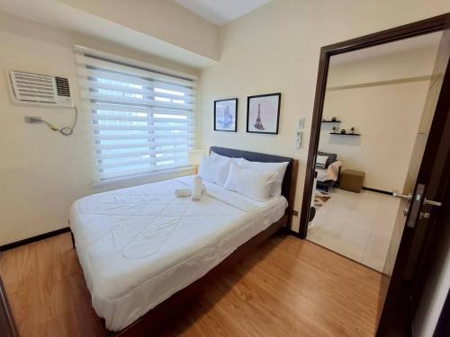 a bedroom with a large white bed with a window at Roomy 1BR Balcony-40sqm-4px-PET-Parking-MOA,PICC,WTC,CCP in Manila