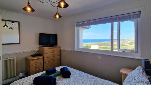 a bedroom with a window with a view of the ocean at Widdy Bay View in Widemouth Bay