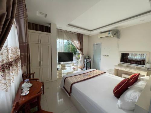 a bedroom with a large white bed and a television at Anh Duong in Lục Yên