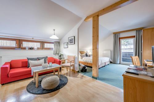 a living room with a red couch and a bed at Inntaler Hof in Seefeld in Tirol
