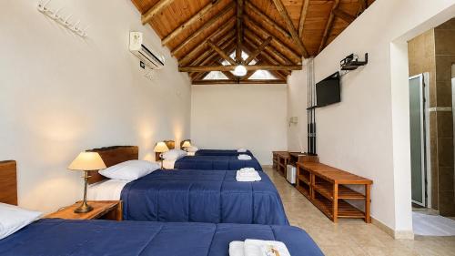 a bedroom with two beds and a television in it at Rincon del Dorado Lodge in Goya