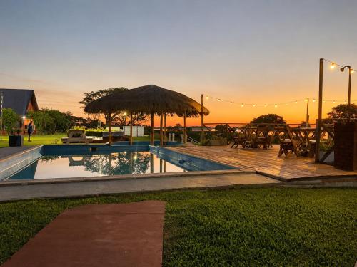 a swimming pool with a table and an umbrella at Rincon del Dorado Lodge in Goya