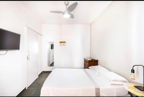 a white bedroom with a bed and a flat screen tv at Casa Aconchego in Itu