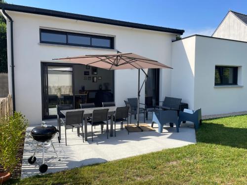 a patio with a table and chairs and an umbrella at Le Cottage Bigouden in Combrit