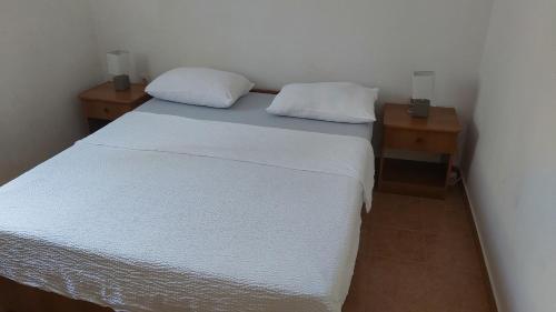 a bedroom with a white bed and two night stands at Apartments Tomas in Ugljan