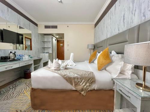 a bedroom with a large white bed and a desk at Zowar Alalami Hotel - فندق زوار العالمي in Medina