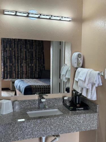 a bathroom mirror with a sink in a hotel room at Villa West Inn in Odessa