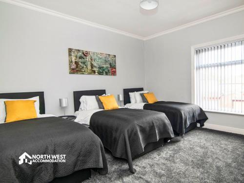 a bedroom with two beds and a painting on the wall at Comfy 2-Bedroom Family & Contractor Home in Bolton with Free Wi-Fi and Street Parking By North West Accommodation in Bolton